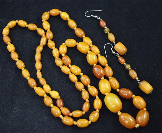 A single strand graduated oval amber bead necklace and a pair of amber drop earrings,